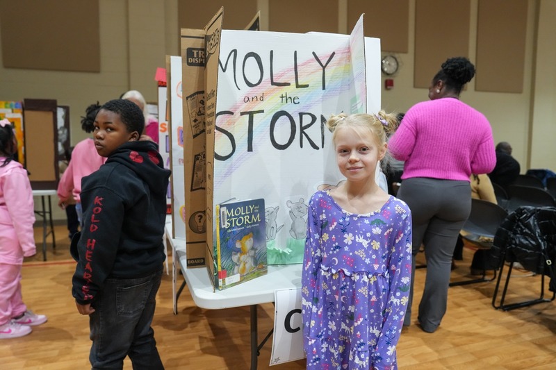 Students standing near their reading fair projects.