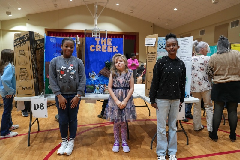 Students standing near their reading fair projects.