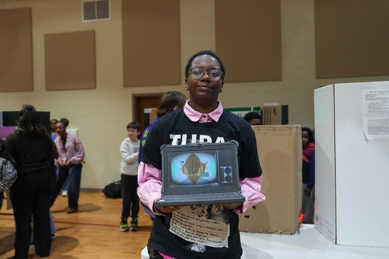Student standing near their reading fair project.