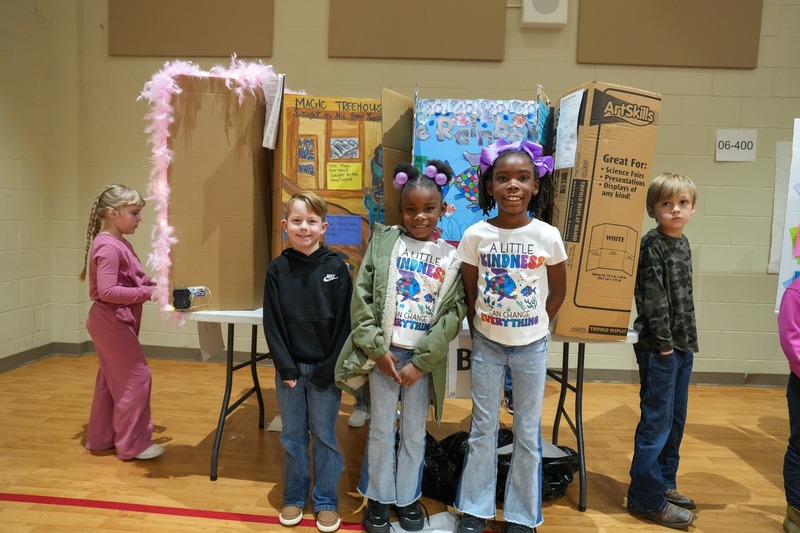 Students standing near their reading fair projects.