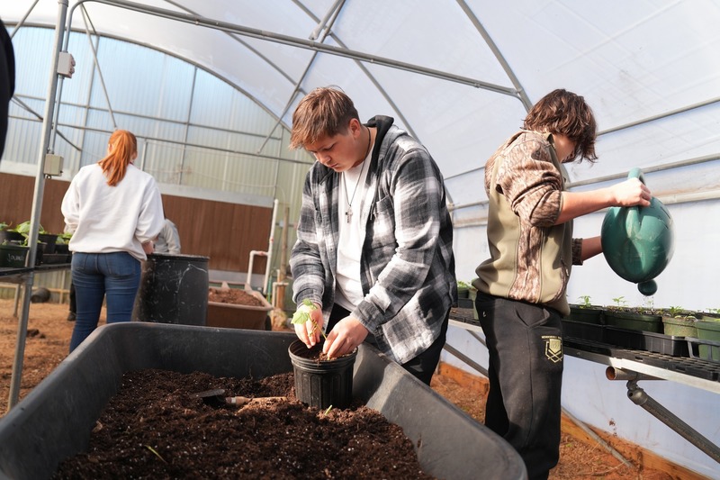 A student is placing soil in a flower pot.