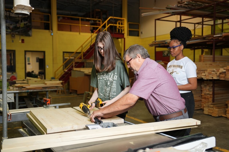 Instructor is teaching a student to use a power drill.