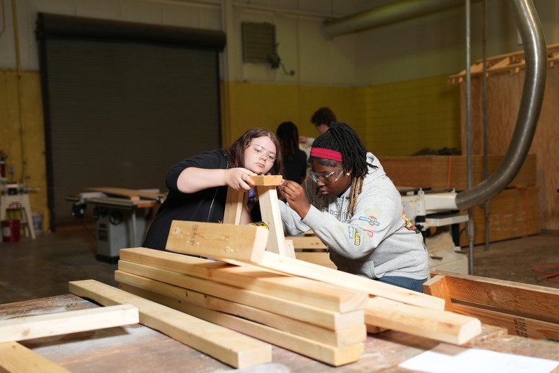 Two students measure wood