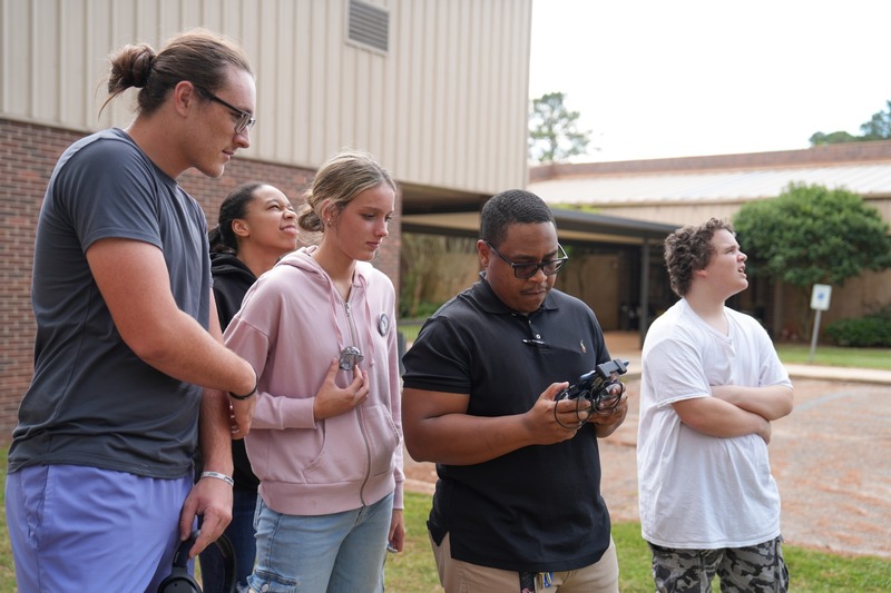 Unmanned Aircraft Systems instructor showing a drone to a group of students.