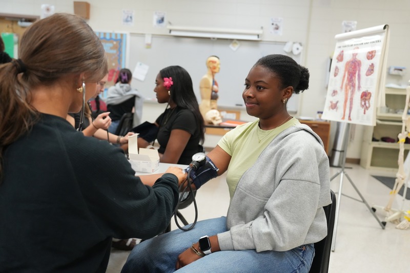 Students in Health Sciences practices using stethoscope.