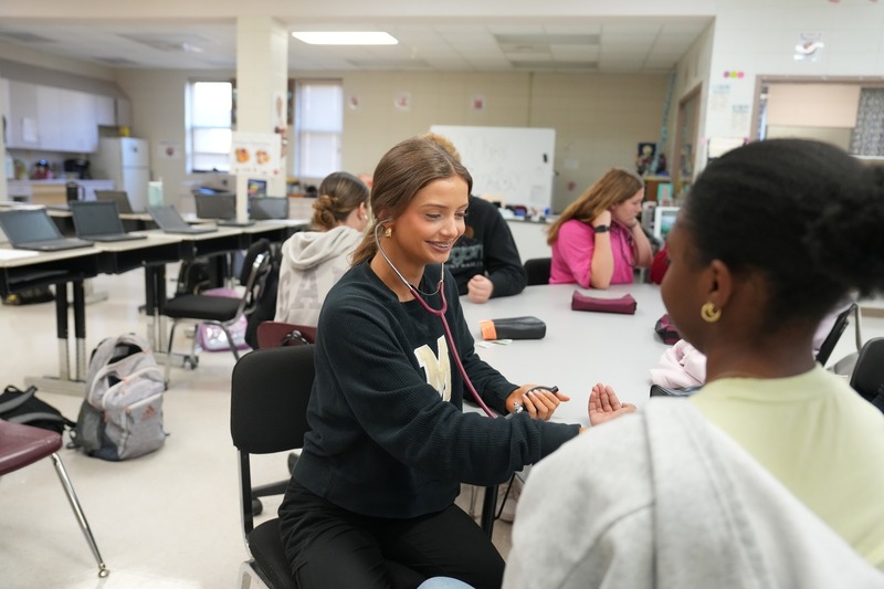 Students in Health Sciences practices using stethoscope.