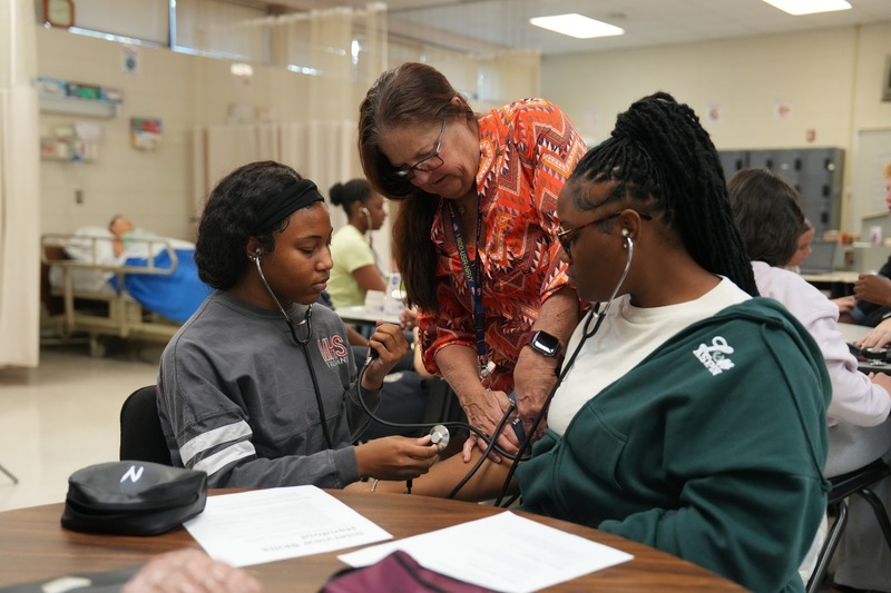 Students in Health Sciences practices using stethoscope.