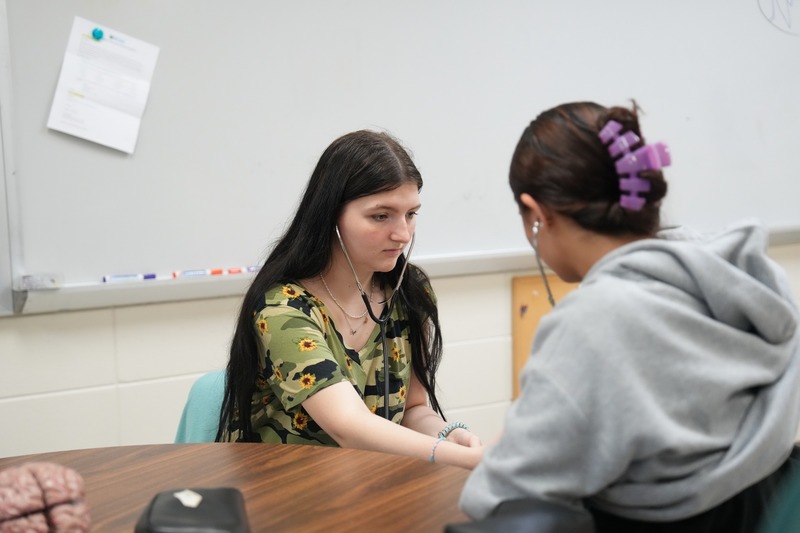 Students in Health Sciences practices using stethoscope.
