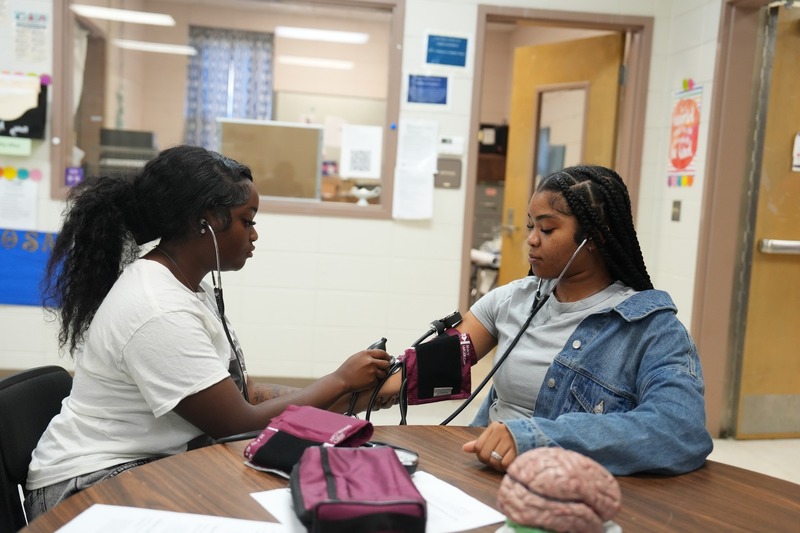 Students in Health Sciences practices using stethoscope.