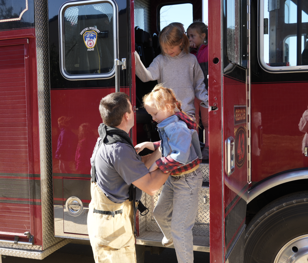 Fireman helps student off the fire truck.