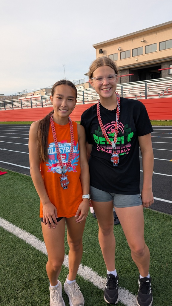 Students posing on track field with rebel chain