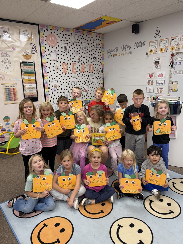 class posing with pumpkin craft and special reader