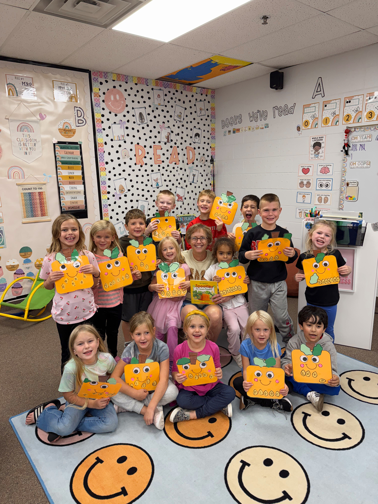 class posing with pumpkin craft and special reader