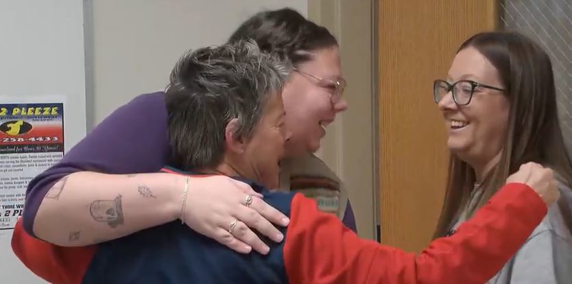 Three women hug each other while smiling