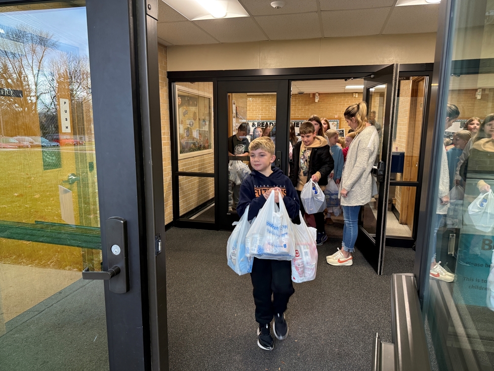 Students at Sunnyside Elementary carry food items outside for donation