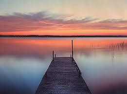 Empty dock over water with a sunset.