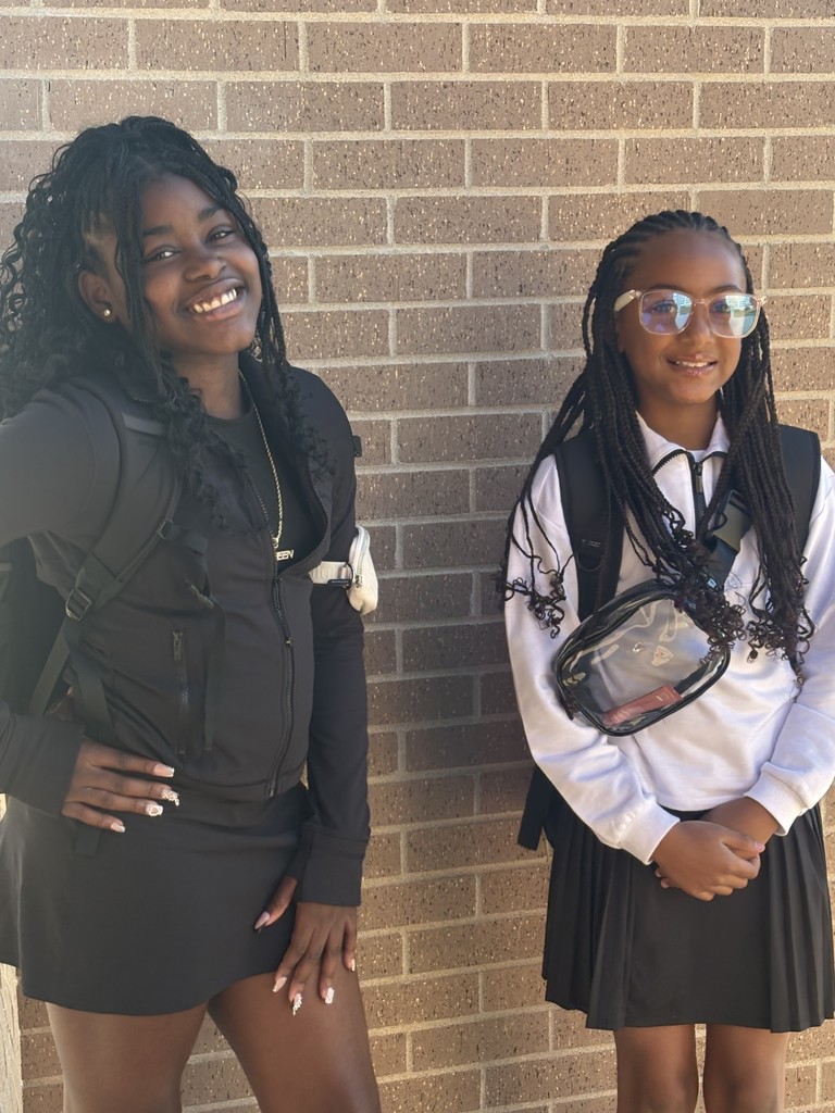 2 students posing in front of a brick wall on the first day of school