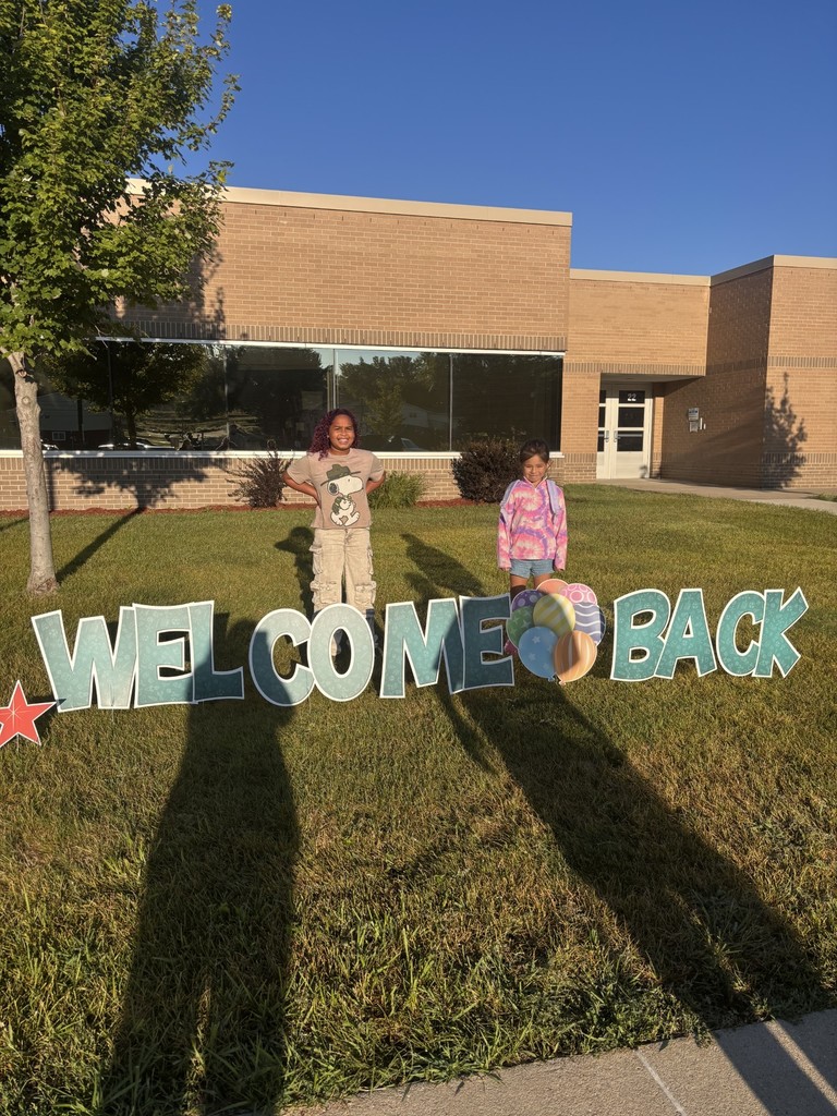 2 students posing behind a sign that says "welcome back"