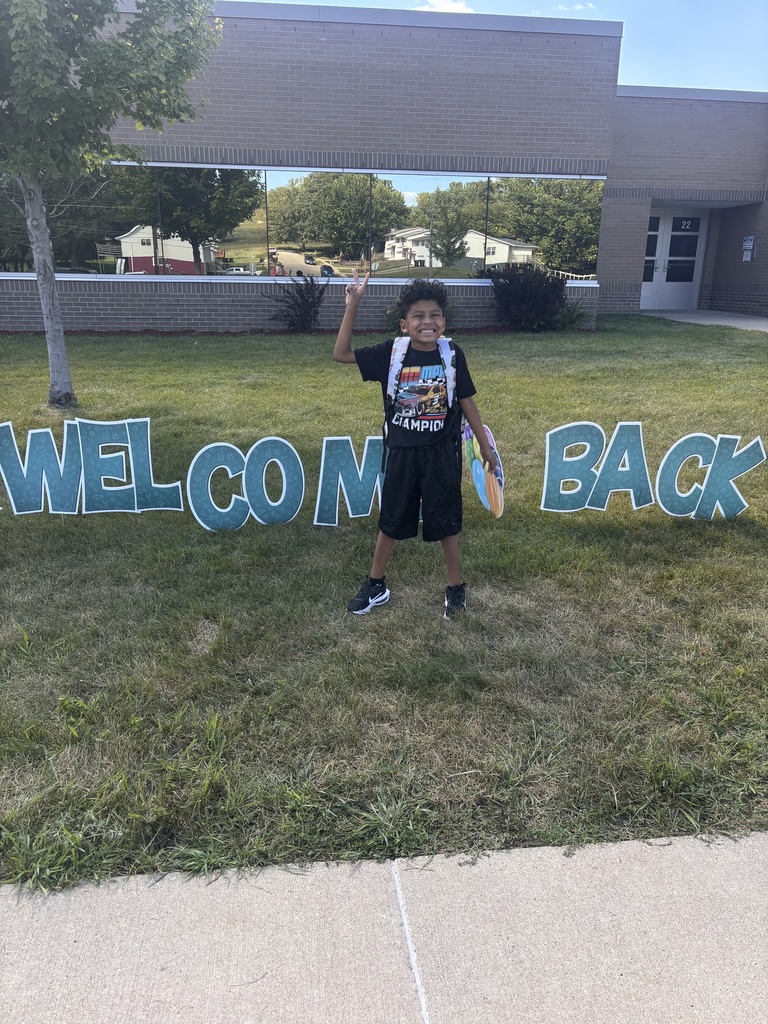 Student standing in front of sign that says "welcome back"