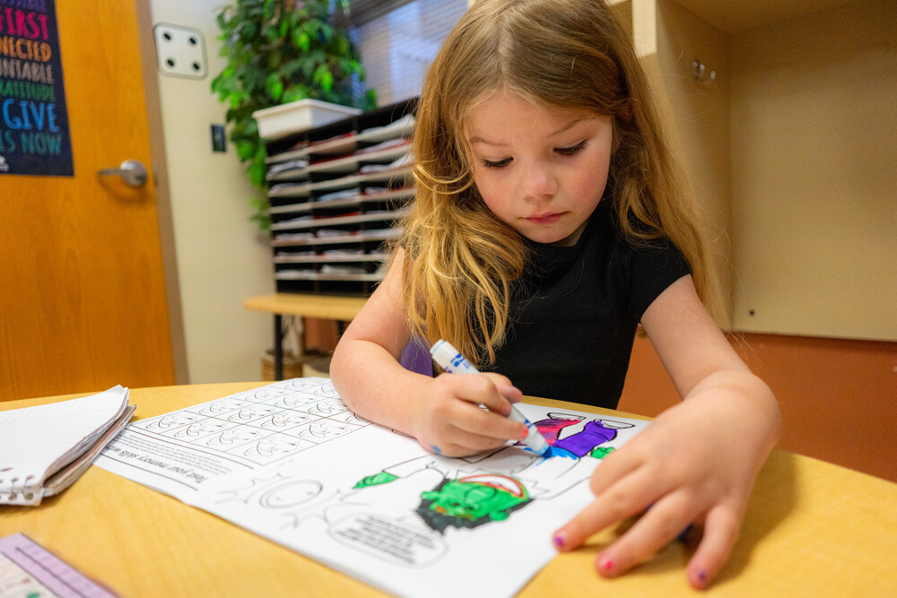 Elementary girl using marker to color picture in classroom