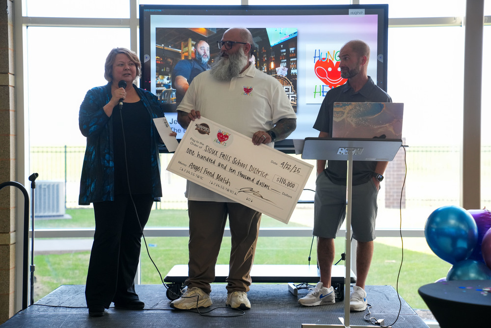 two men stand with big check