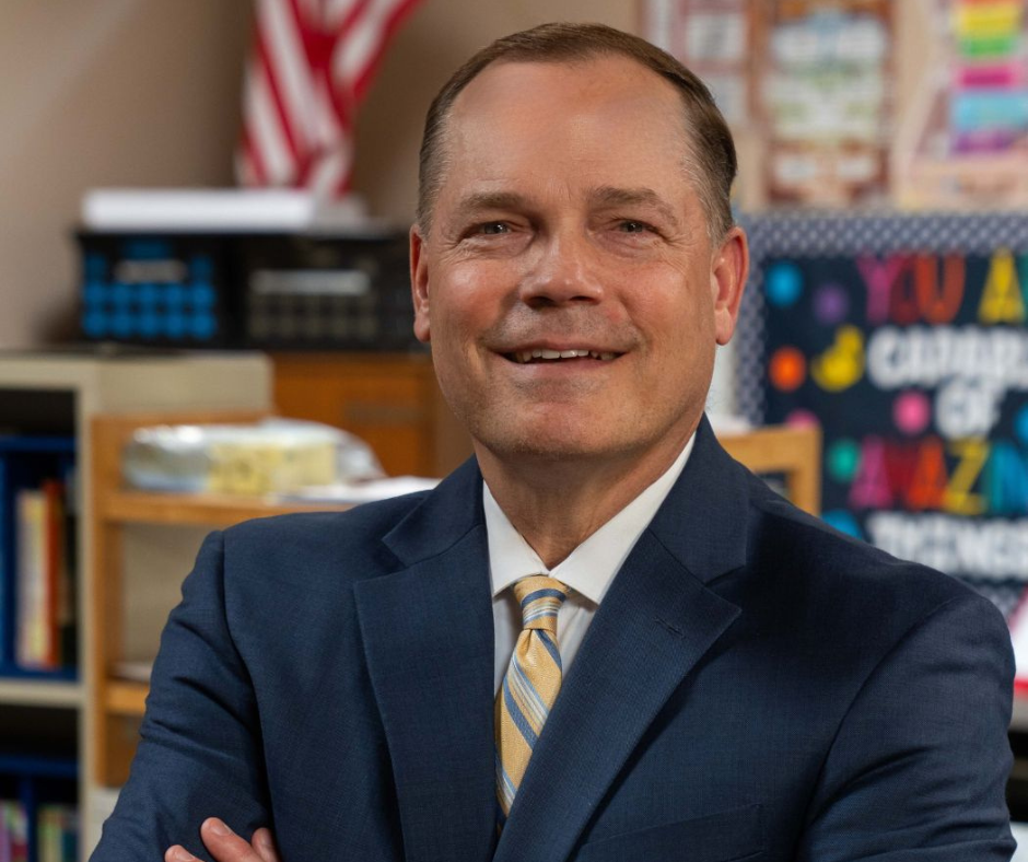 Dr. Jamie Nold, SFSD Superintendent, smiling with arms crossed in front of classroom bulletin board