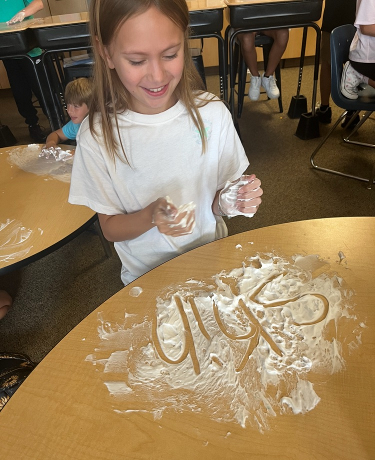 5th graders working on guided spelling using shaving cream on a table. 