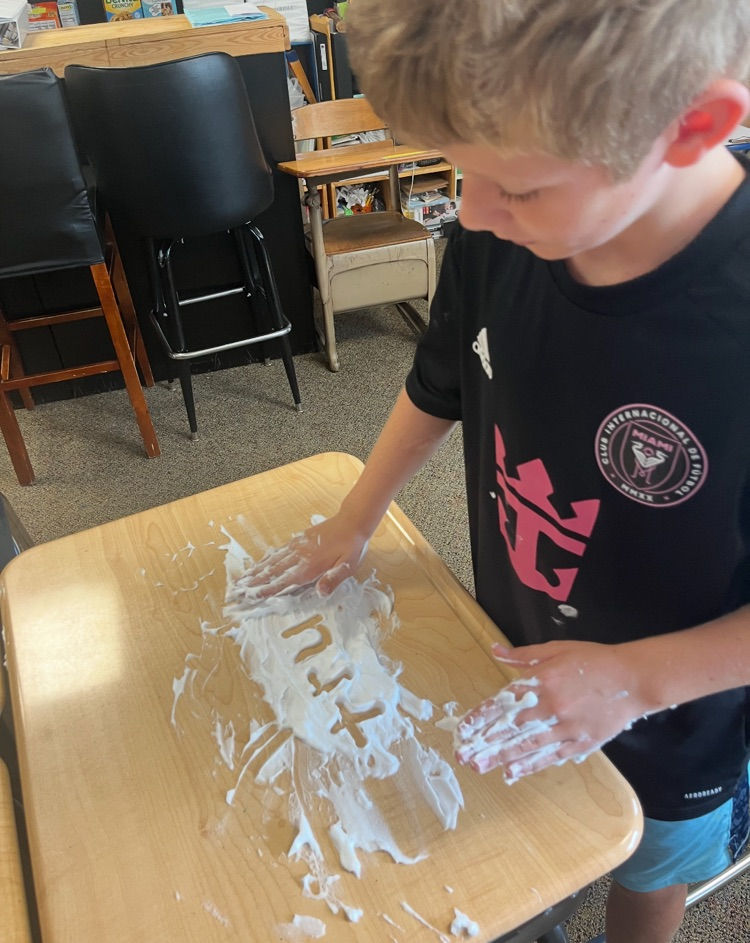 5th graders working on guided spelling using shaving cream on a table. 