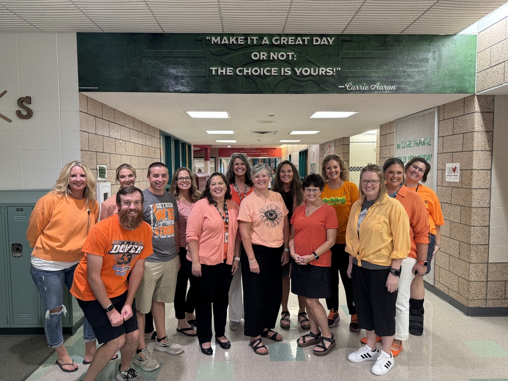 A large group of Memorial Middle School staff wearing orange shirts are gathered together in the school's common area, smiling for a group photo to commemorate Orange Shirt Day.