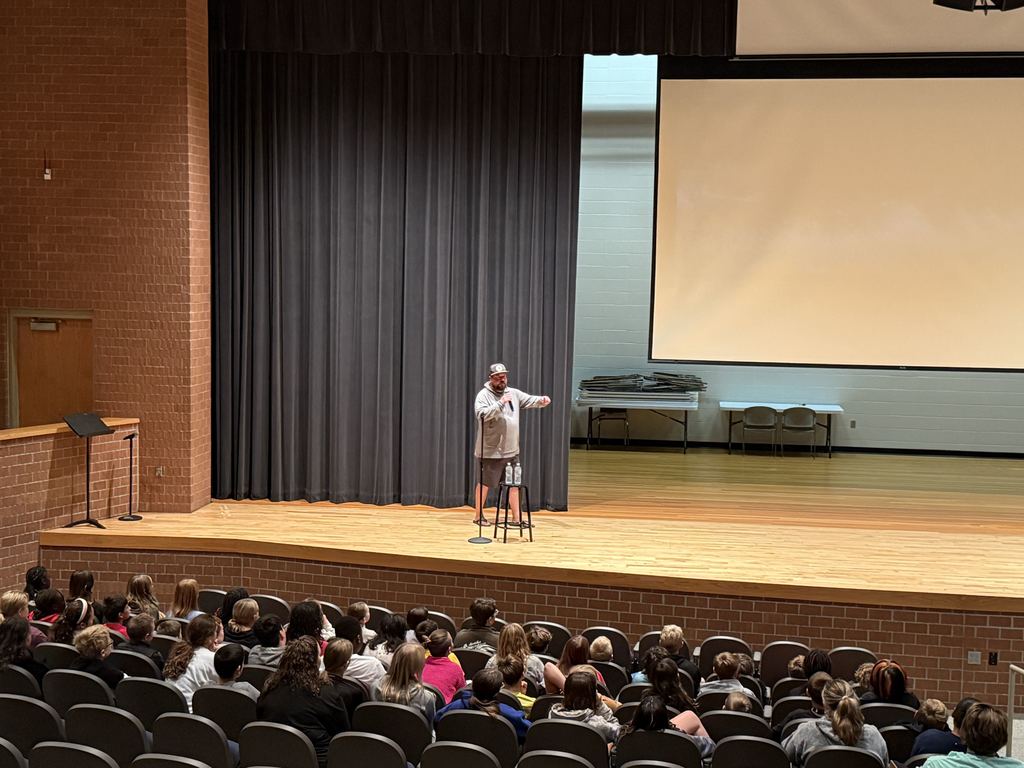 Chris Chittick gestures toward a screen showing tornado footage as students watch intently.