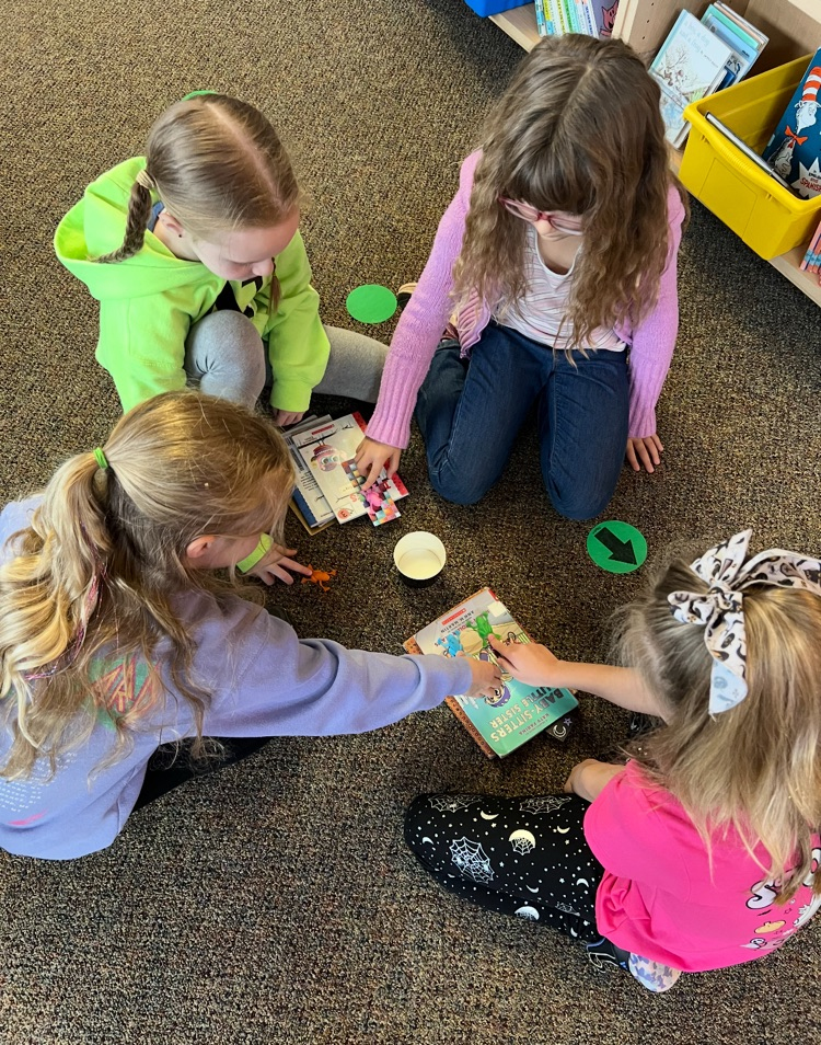 students working in a group to get a toy frog into a cup