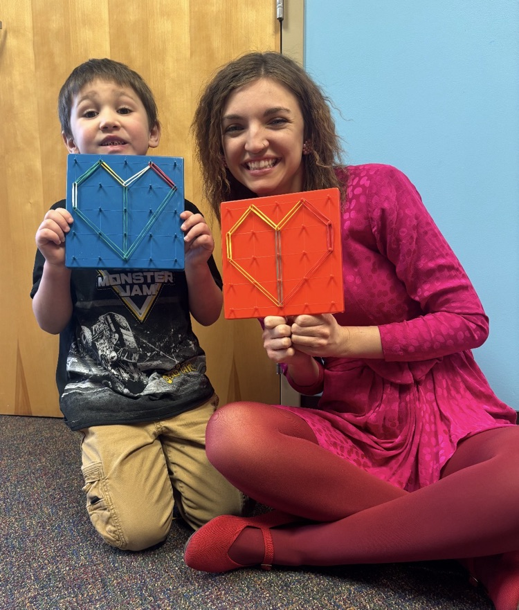 photo of a child and a teacher making hearts