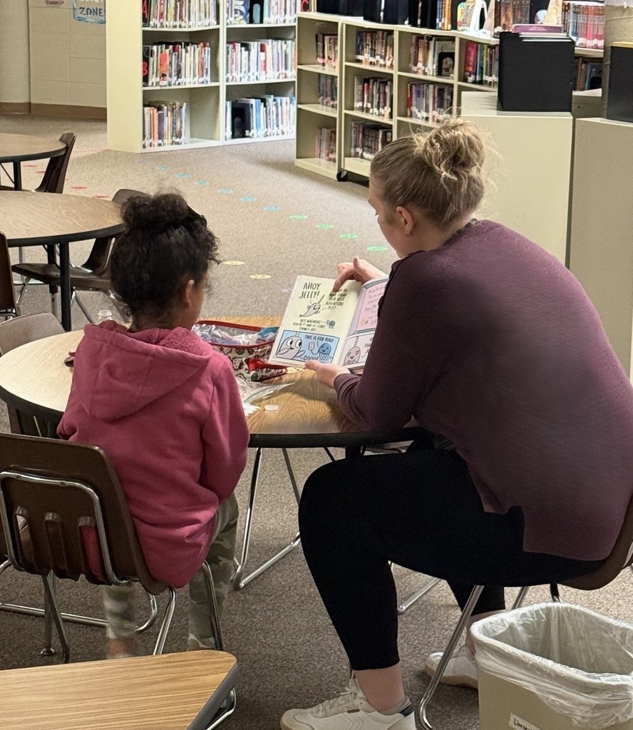 Librarian and child reading together