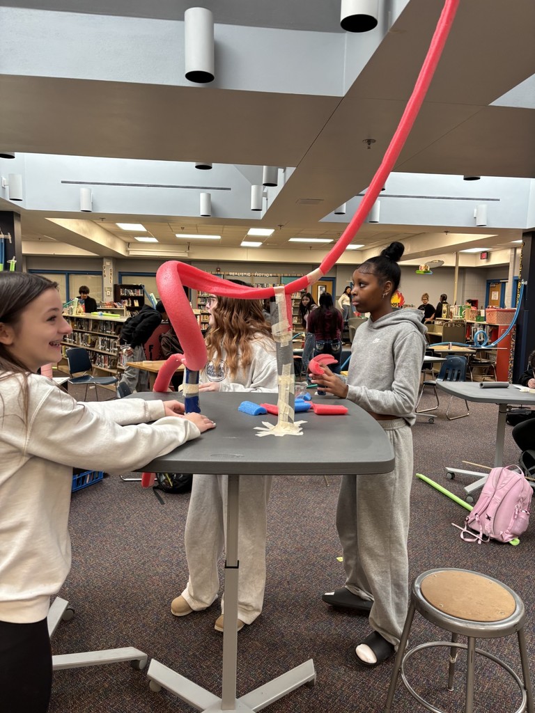 Students standing with a pool noodle roller coaster