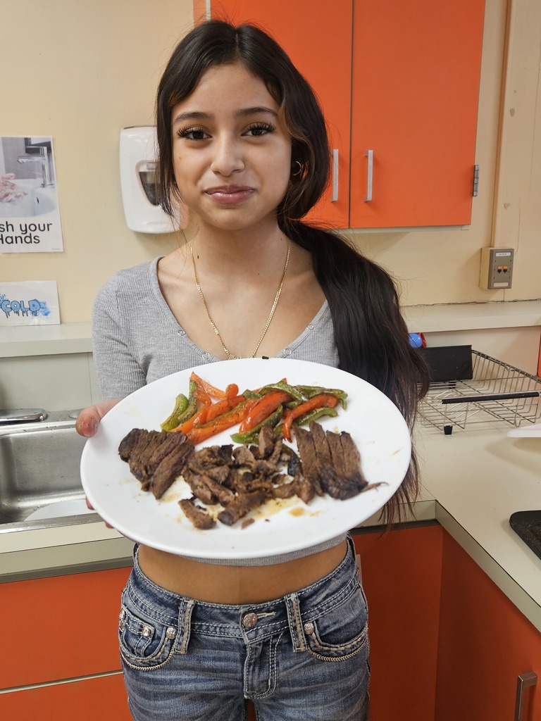 A girl holding a plate showing off the steak and peppers