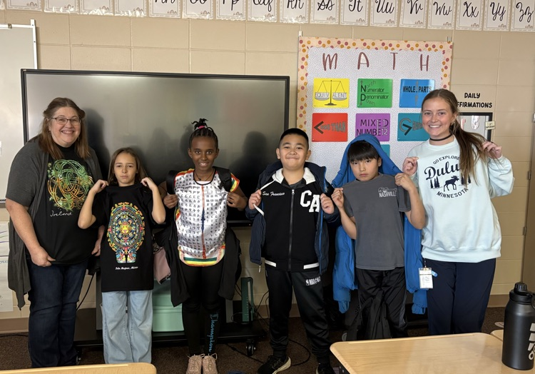 two staff members and 4 students showing off their travel shirts