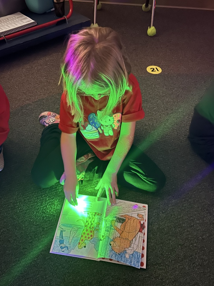 a kindergartner reading with her finger flashlight 
