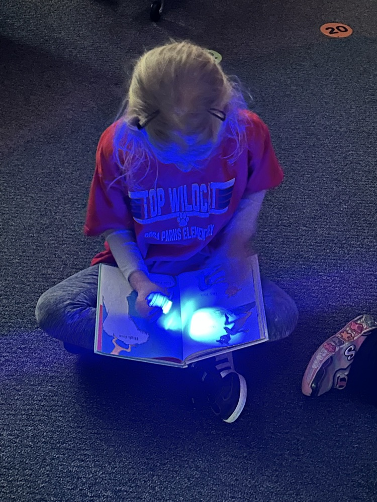 a kindergartner reading with her finger flashlight 