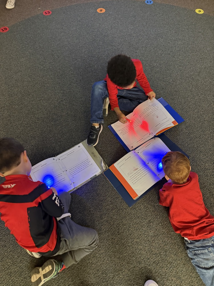 a group kindergartners reading with their finger flashlight 