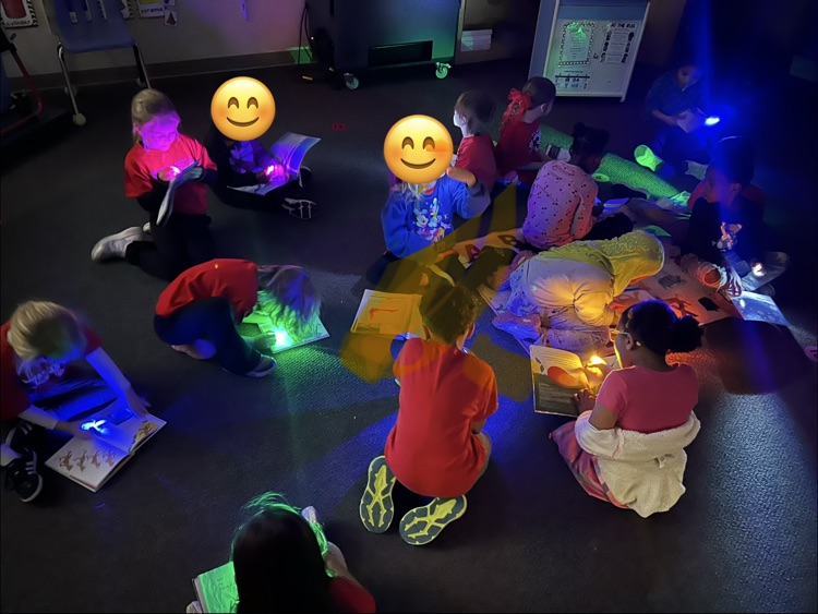 a group kindergartners reading with their finger flashlight 
