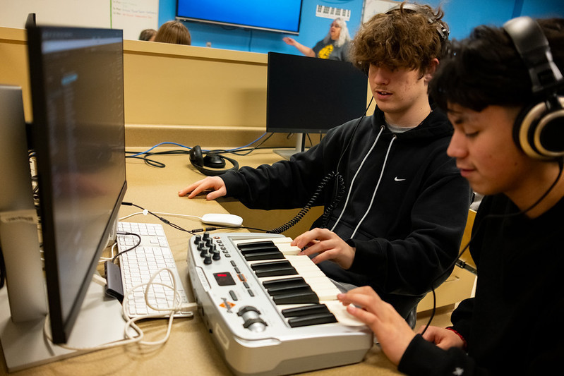 2 students sitting and creating their music to edit