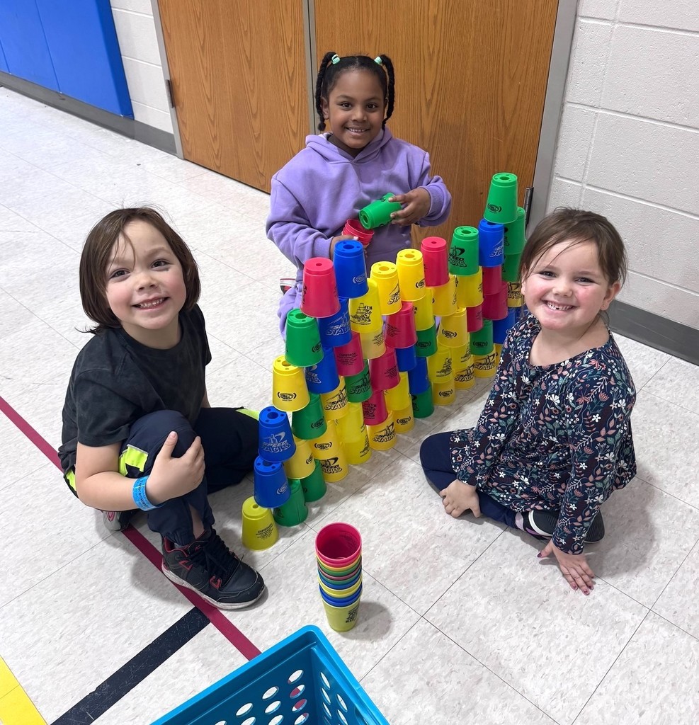 Kindergarten students building towers out of plastic cups. 