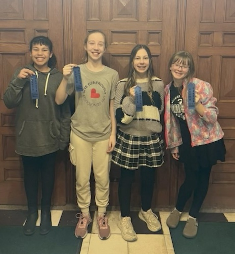 students holding a ribbon they won in a competition.