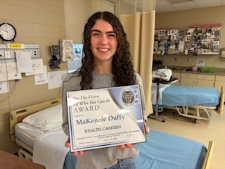 student posing with her award in class