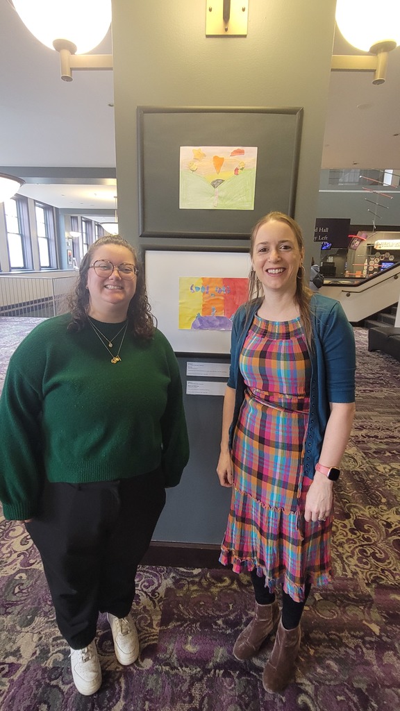 art teachers standing next to art exhibit