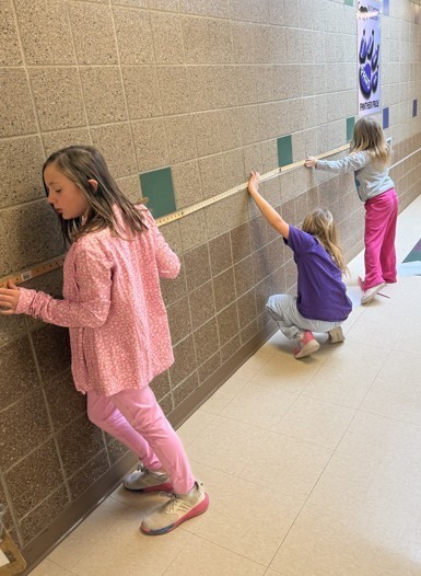 students measuring a distance on the wall