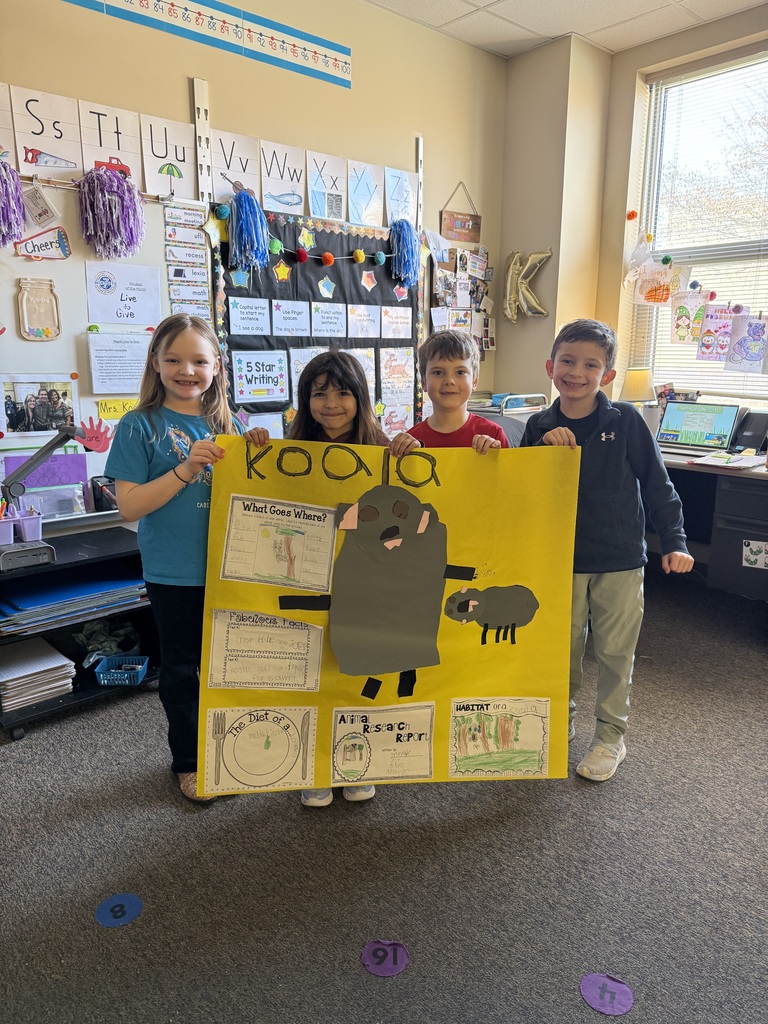 students showing the animal poster they made