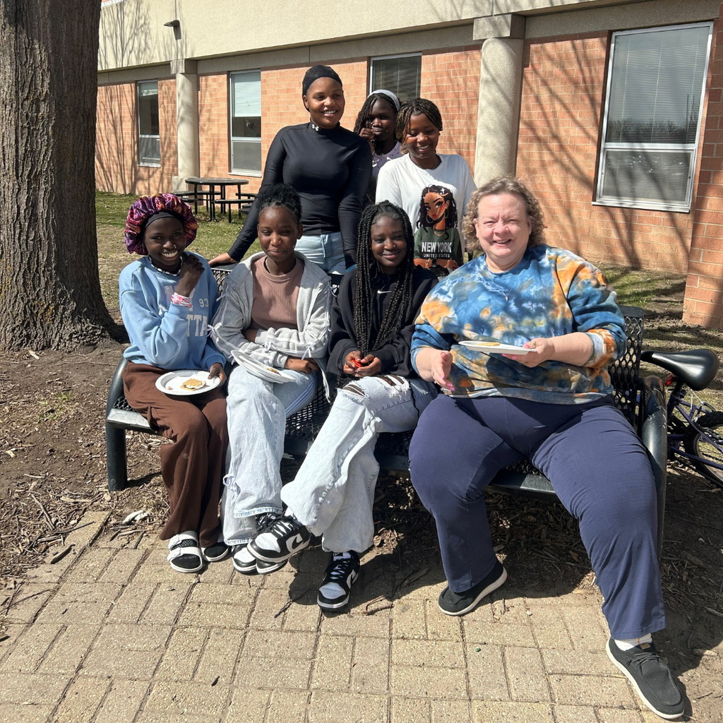 Students sitting on the bench with Ms Cheryl