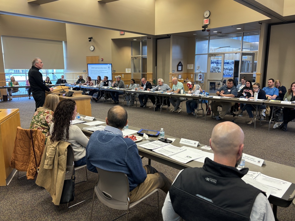 Members of the SFSD Facilities Task Force sit at a long table eagerly listening to the speaker at the front of the room