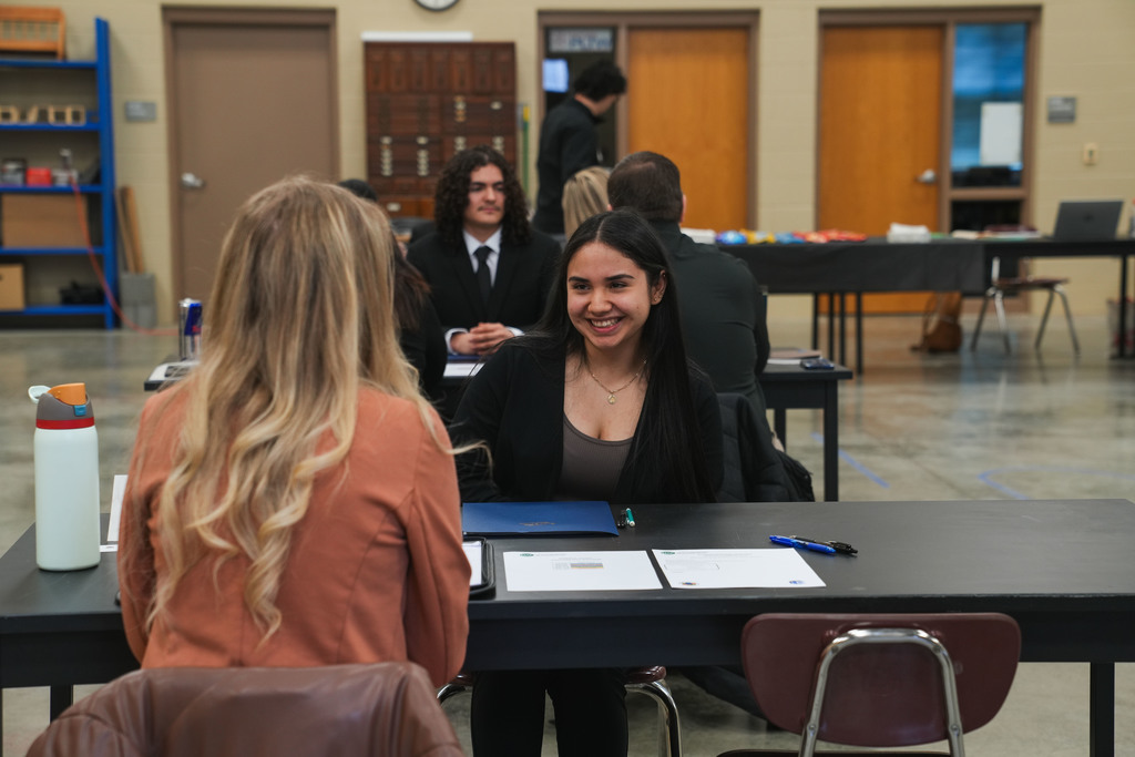 Academy of Finance student laughingly smiles at a women across the table from her during a mock interview at the CTE Academy.